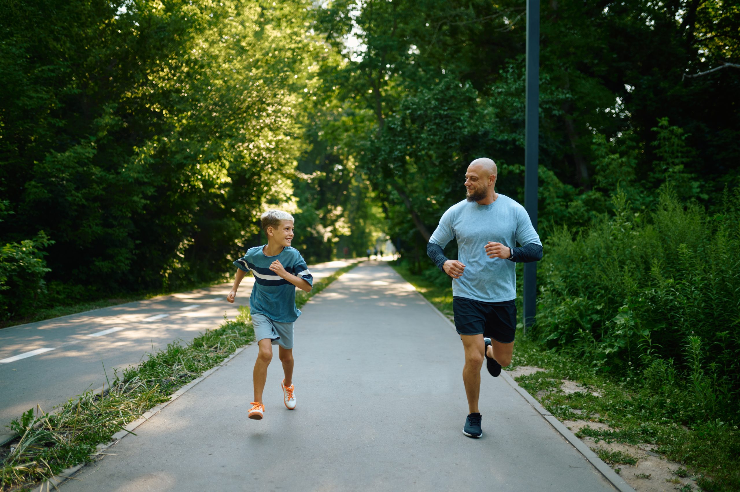 Father and son running on walking path in park
